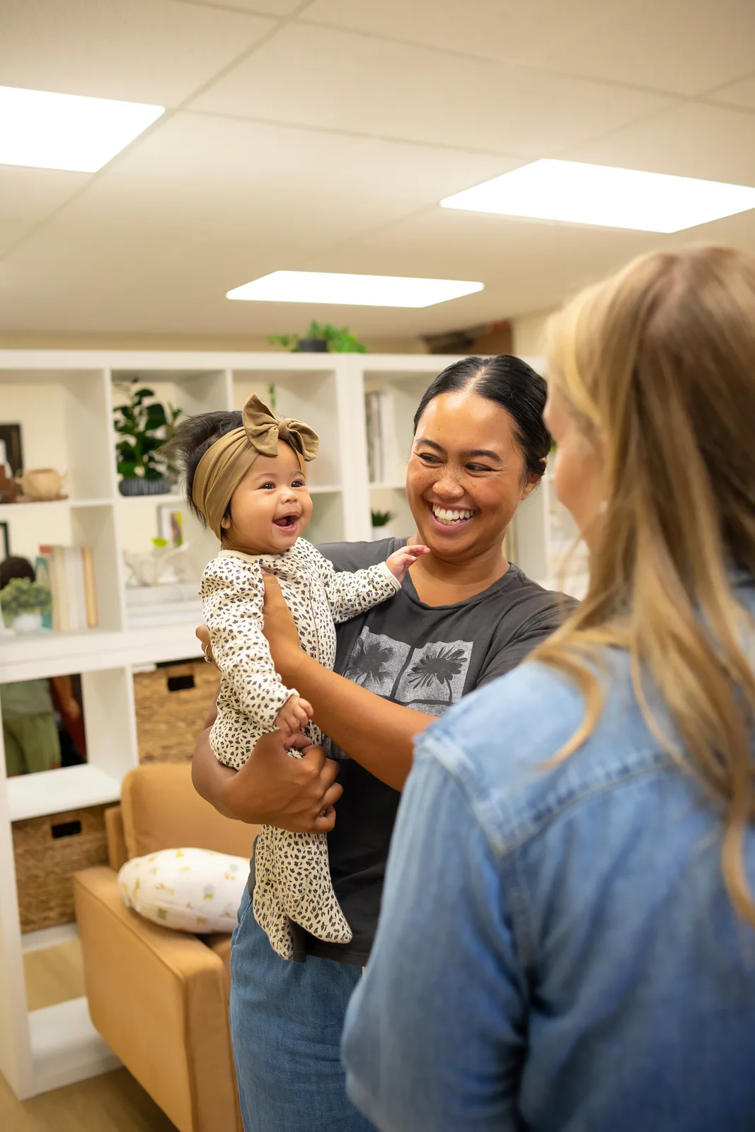 Smiling mother holding her baby while speaking with a chiropractor during an infant visit in Temecula