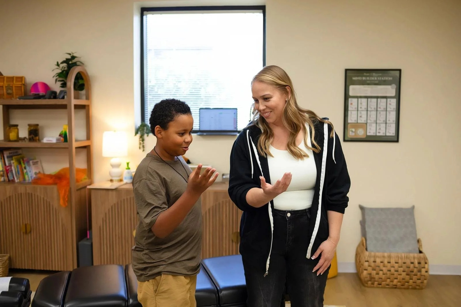 Dr. Jennifer Gordon smiling and gesturing while interacting with a child beside a treatment table