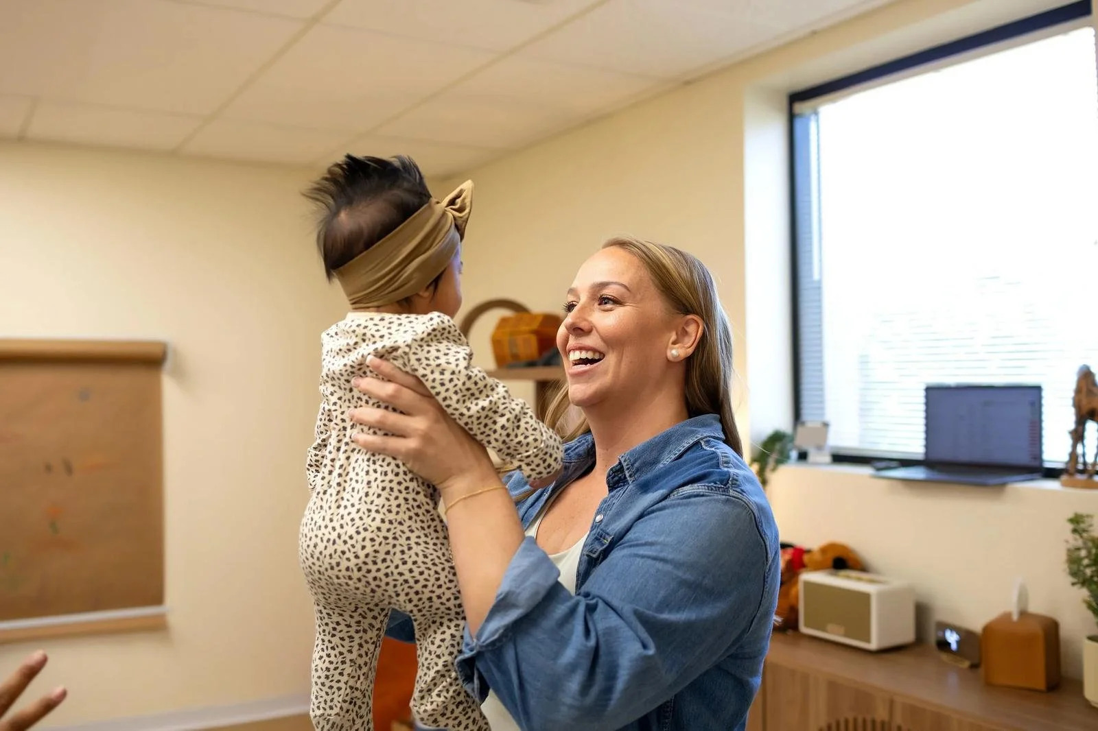Dr. Jennifer Gordon smiling as she playfully lifts an infant in the air