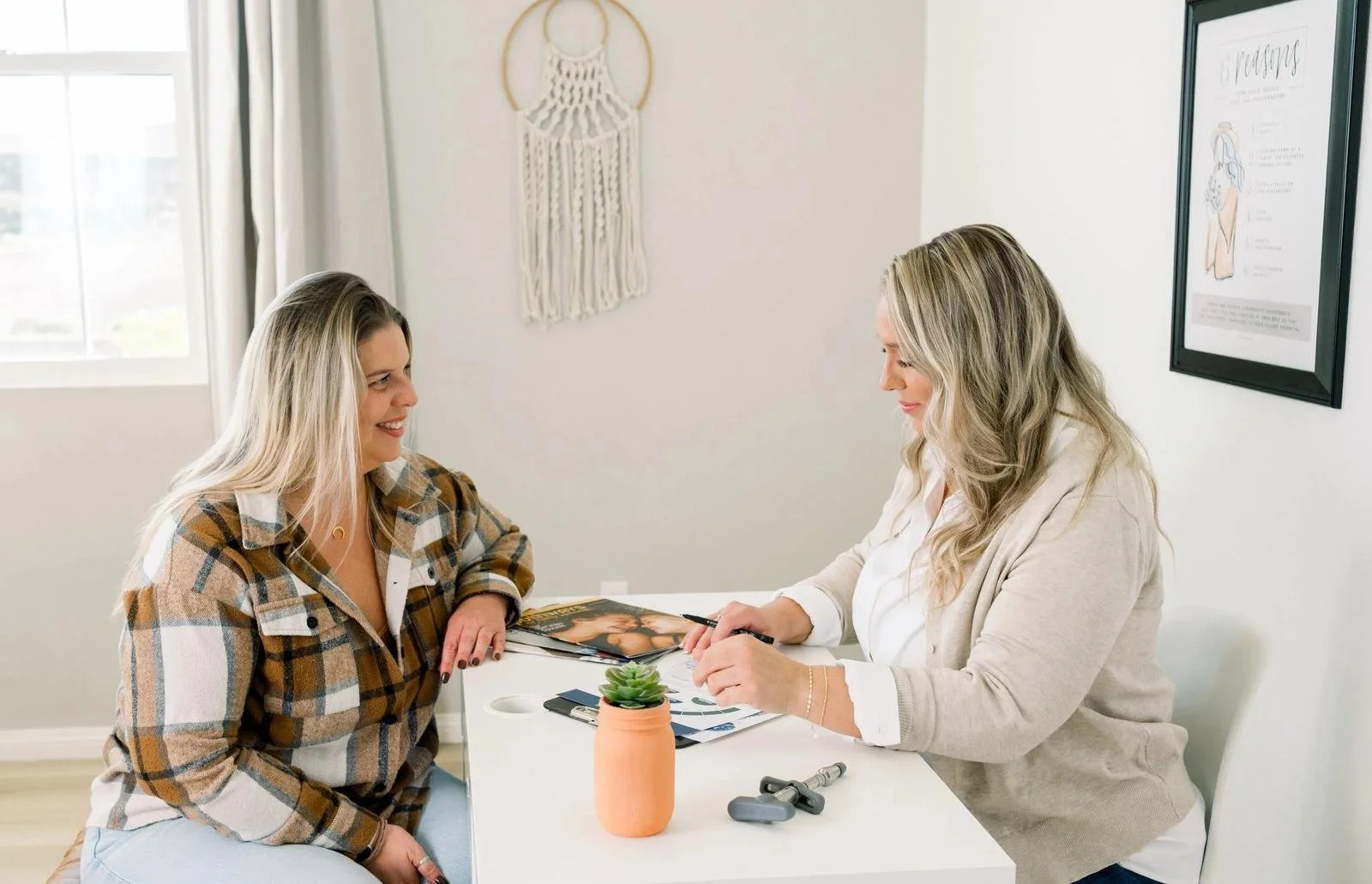 Two women seated at a table reviewing paperwork together in the office
